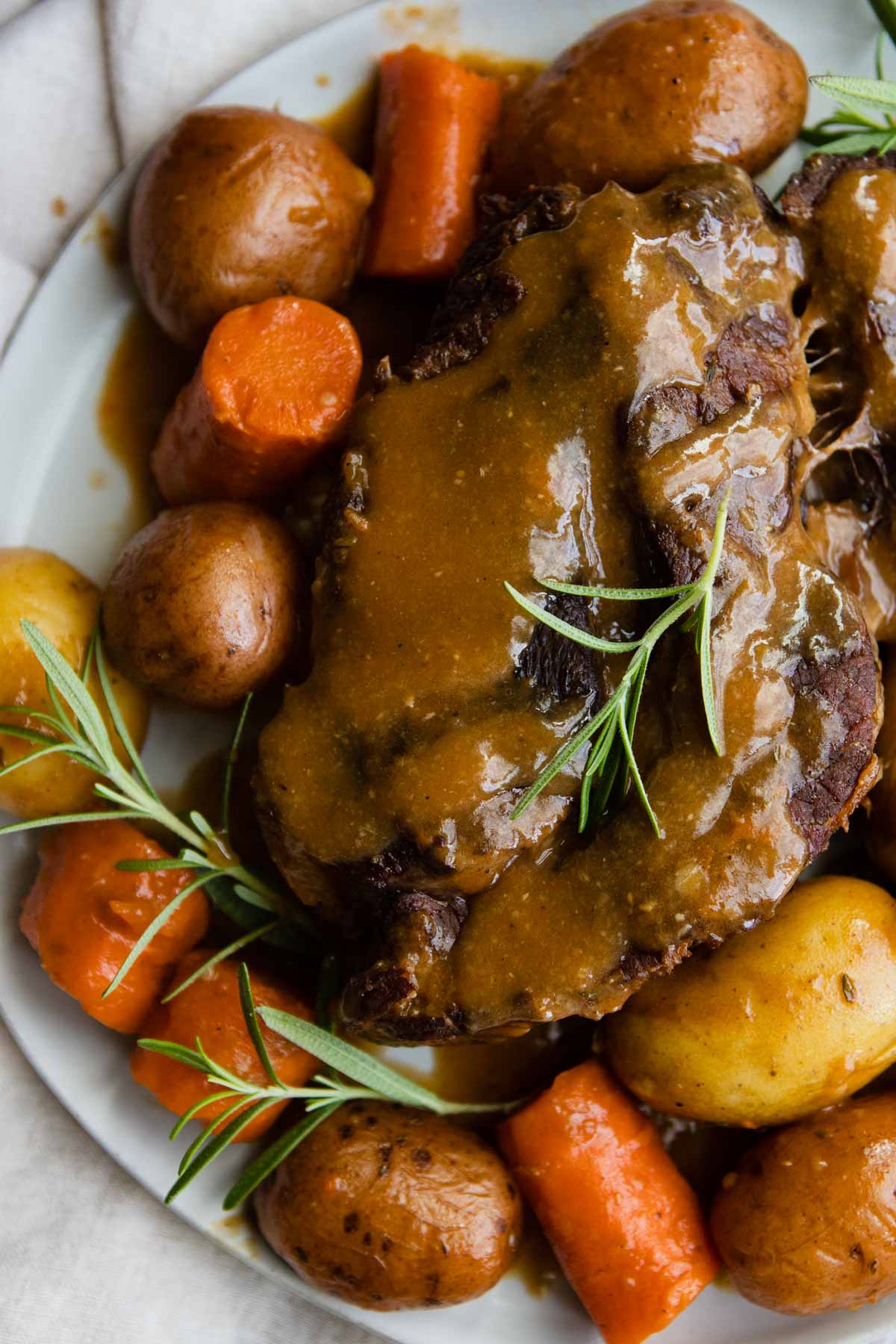 old fashioned pot roast smothered with gravy with potatoes and carrots on a platter