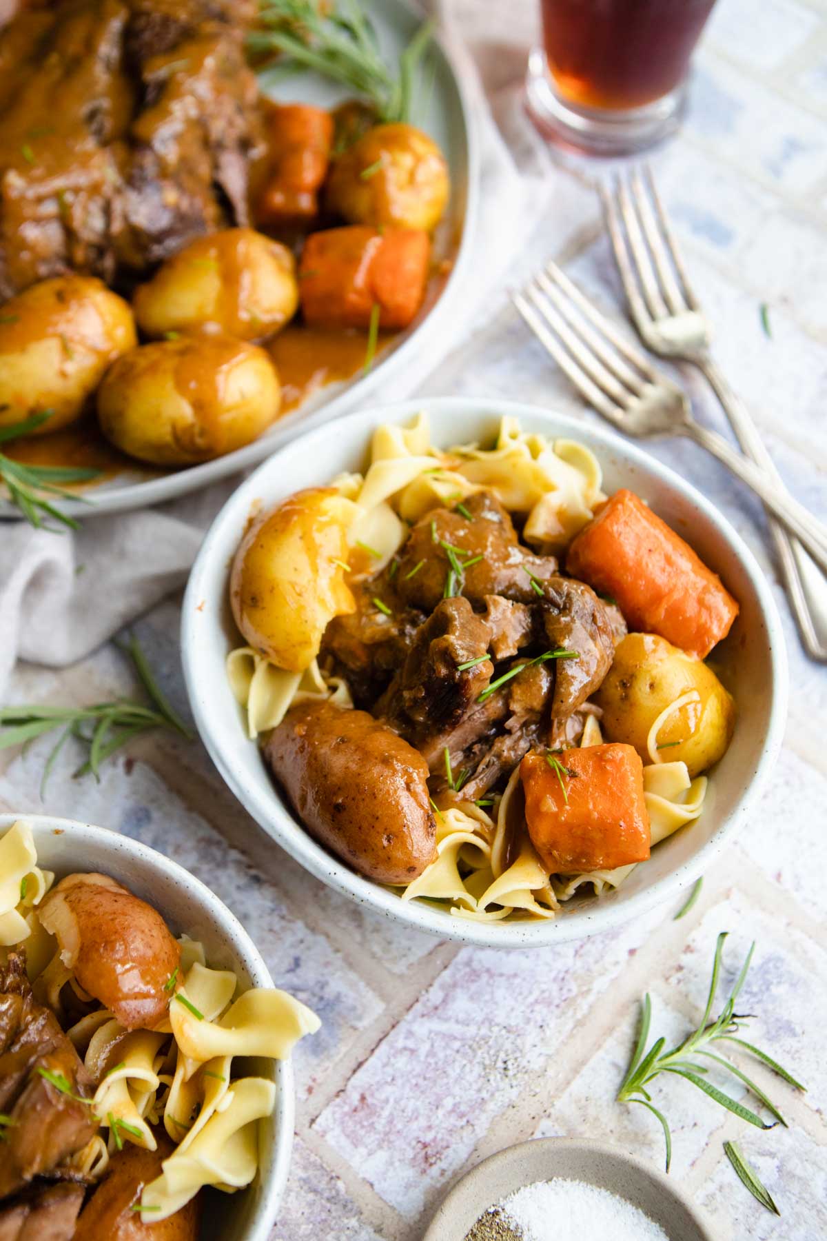bowls of buttered egg noodles with beef roast on top
