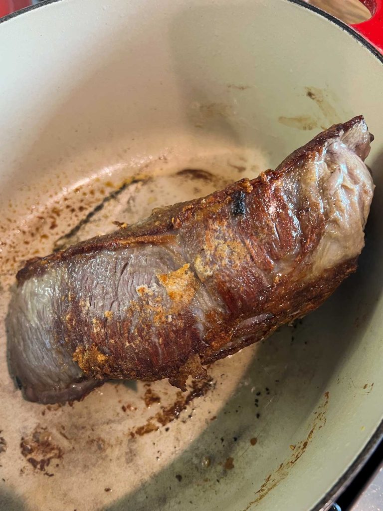 beef pot roast being seared in a dutch oven