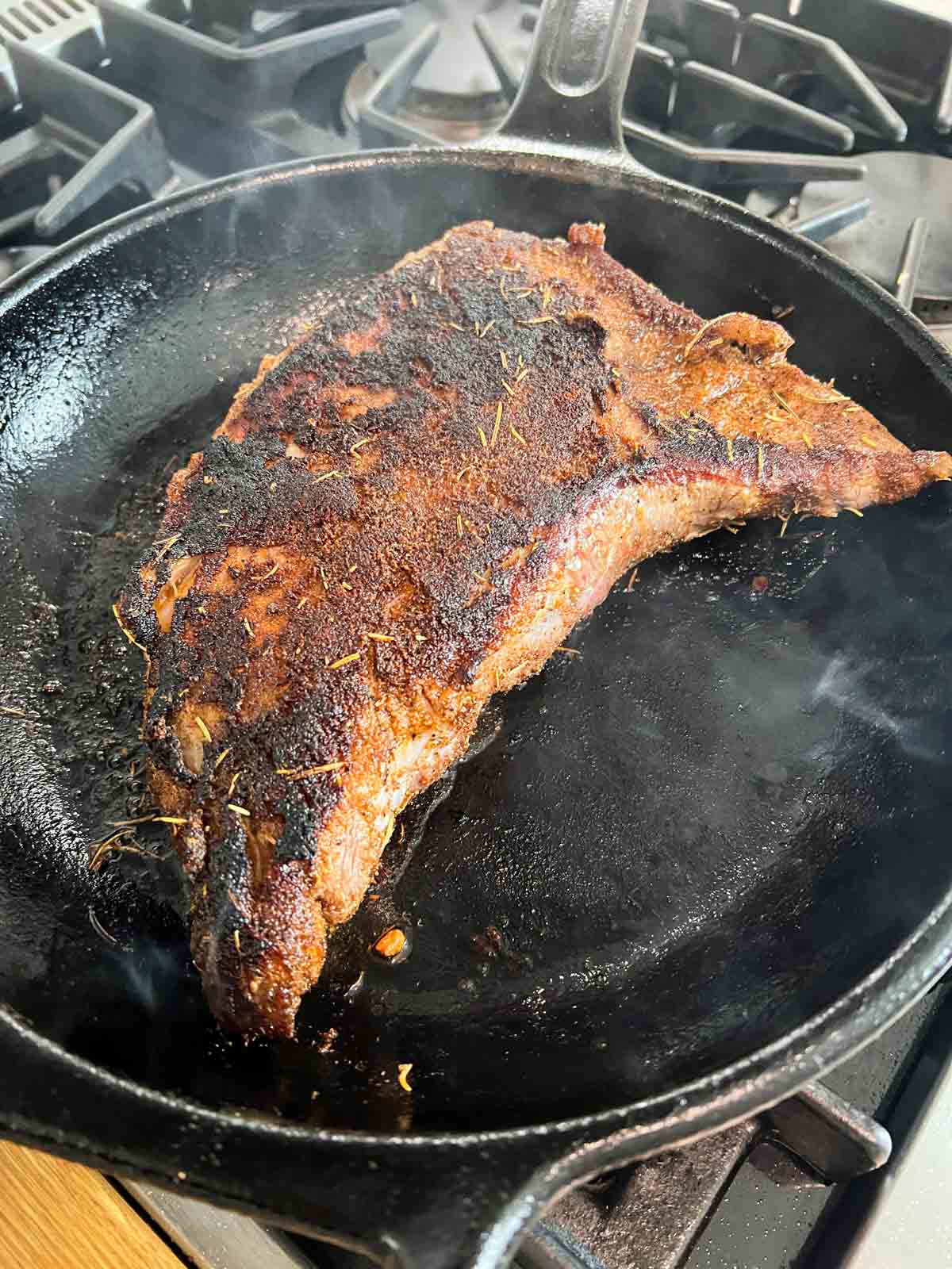 tri tip being seared in a hot cast iron skillet