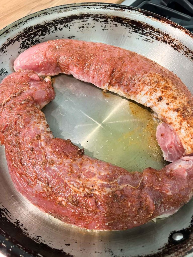 pork tenderloin being seared in a hot pan
