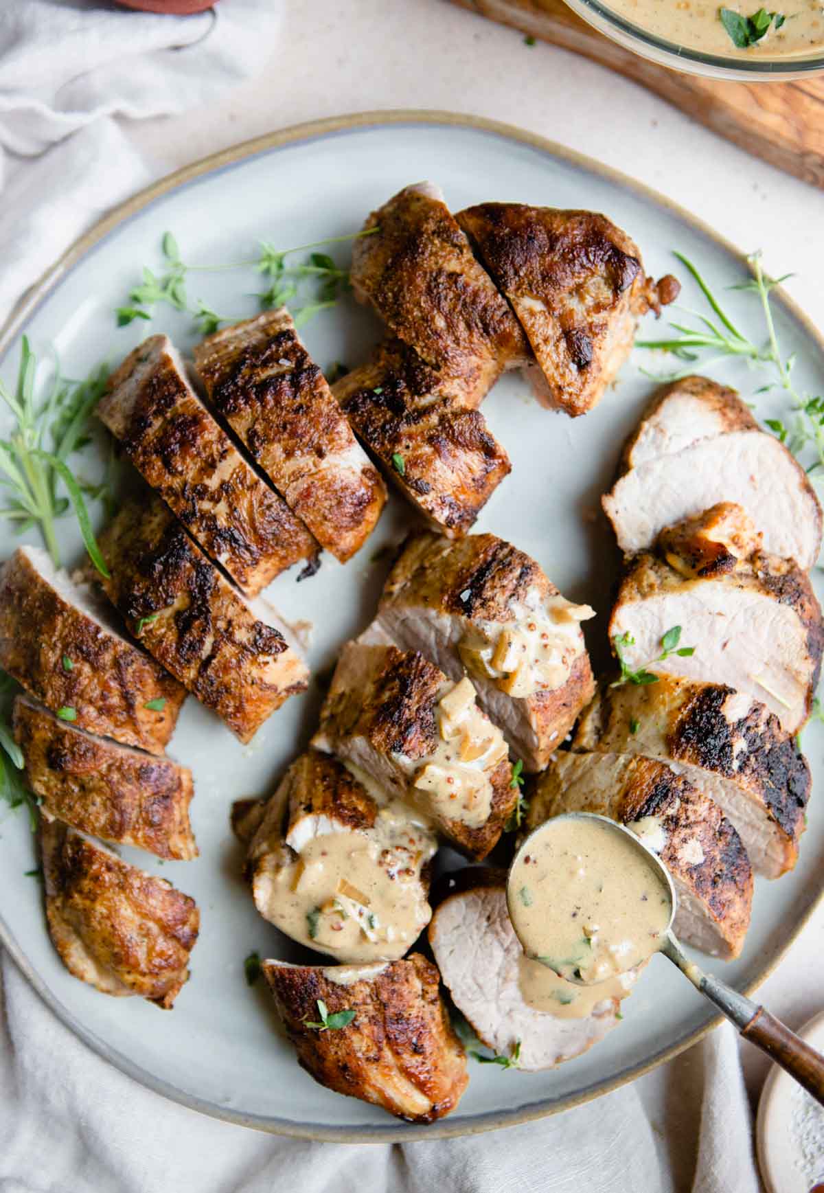 creamy Dijon mustard sauce being poured on top of air fried pork tenderloin 