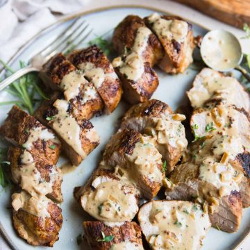 pork tenderloin air fryer recipe cut up and plated with a creamy sauce all over