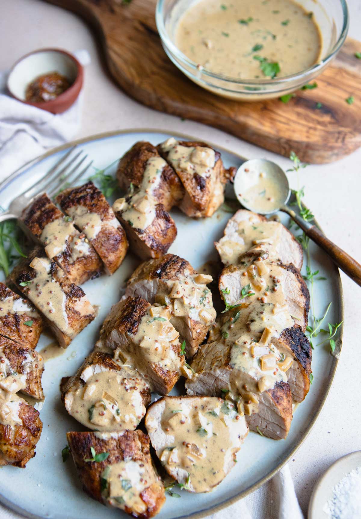 pieces of air fryer pork tenderloin on a gray plate with a mustard cream sauce all over