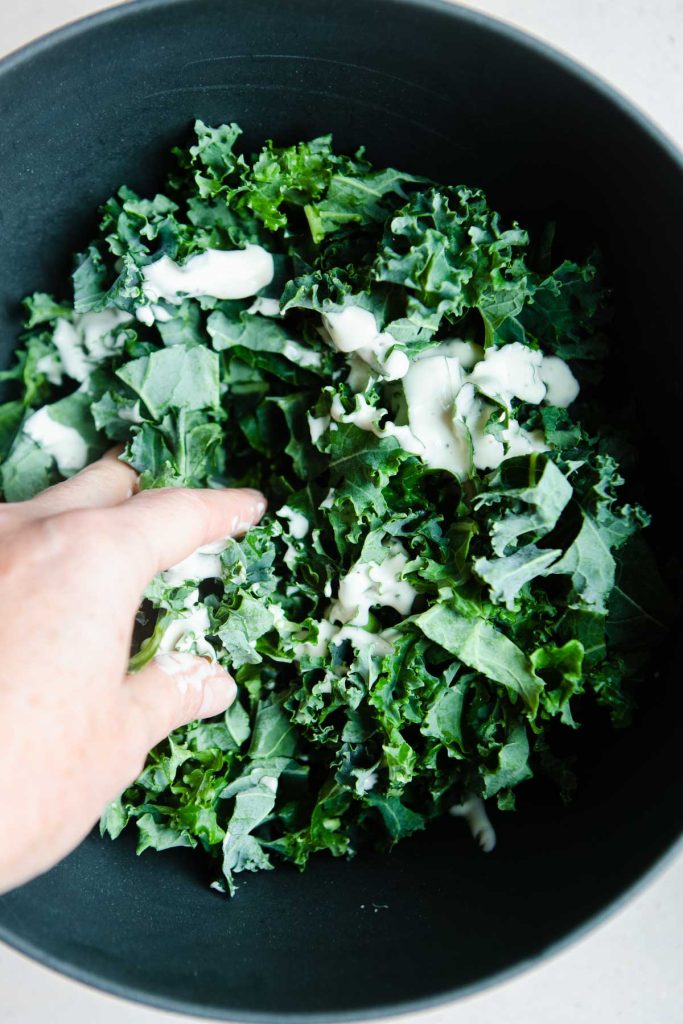 woman massaging salad dressing into kale