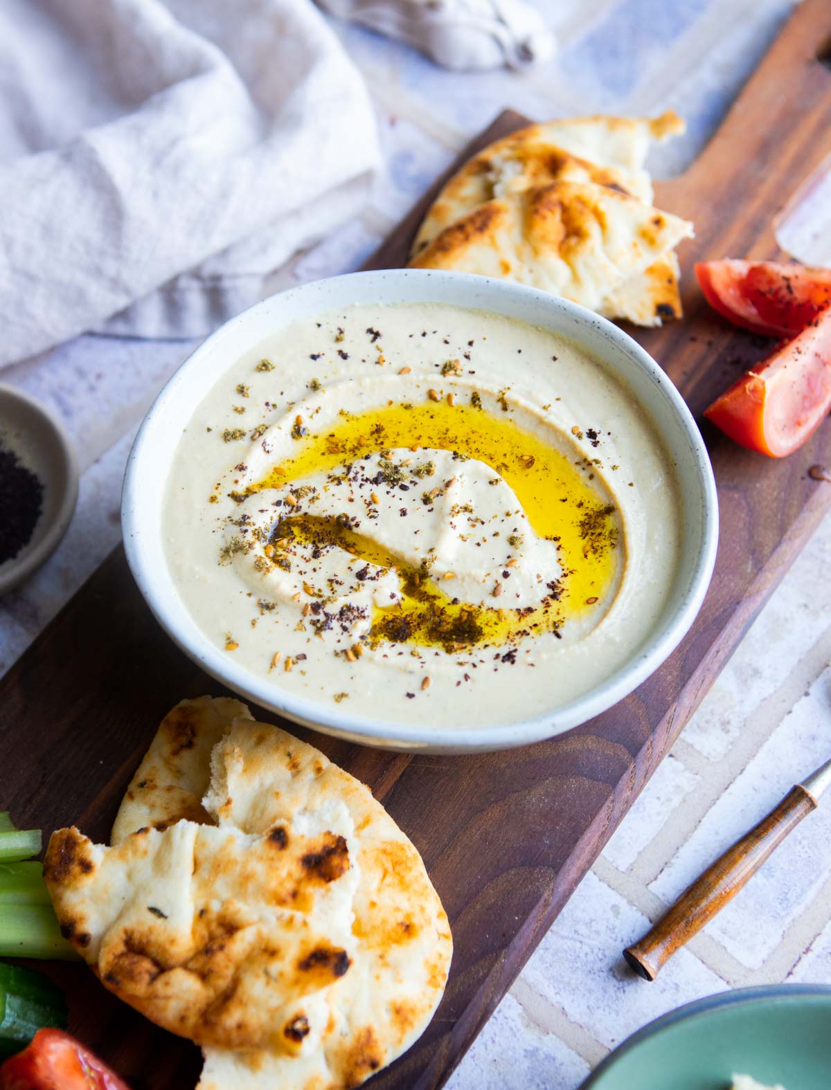 creamy hummus in a beige bowl on a wood board