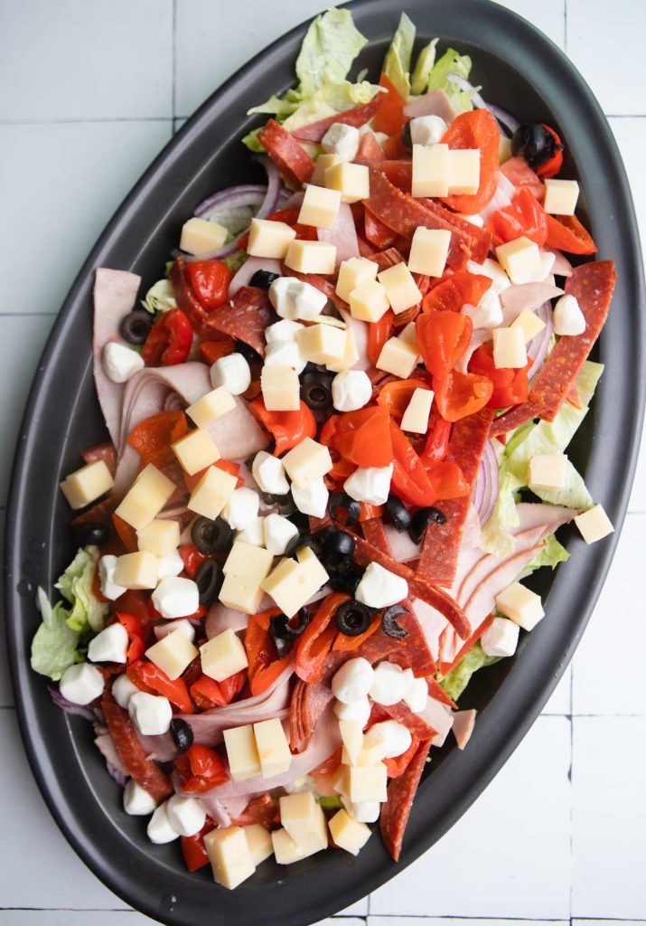 layered ingredients for a subway salad on a black platter