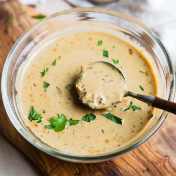 creamy dijon mustard sauce in a glass bowl with wooden spoon