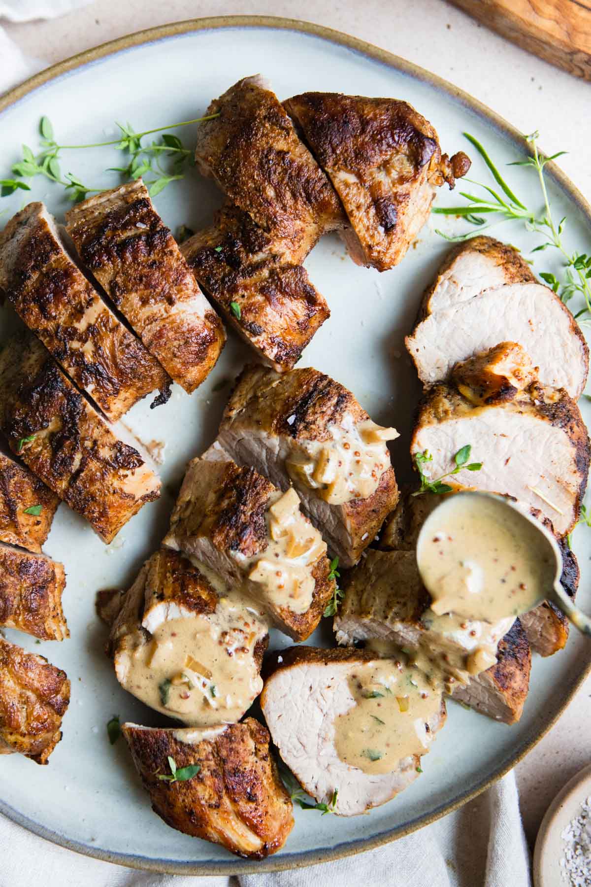 dijon mustard sauce being spooned on pork tenderloin medallions 