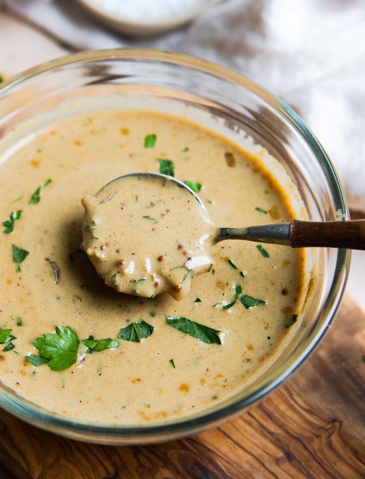 mustard sauce in a clear glass serving bowl on a wood board