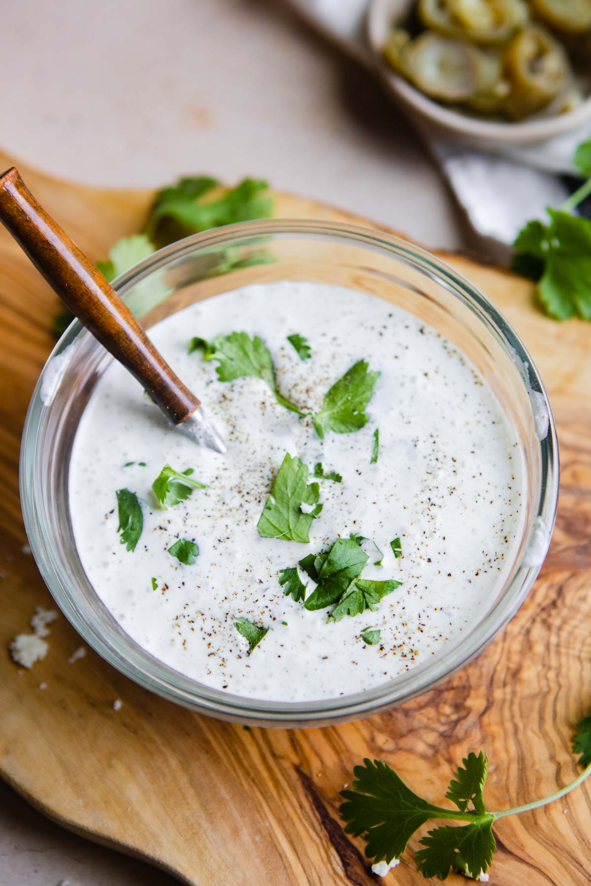 wood spoon in a glass bowl filled with homemade dressing