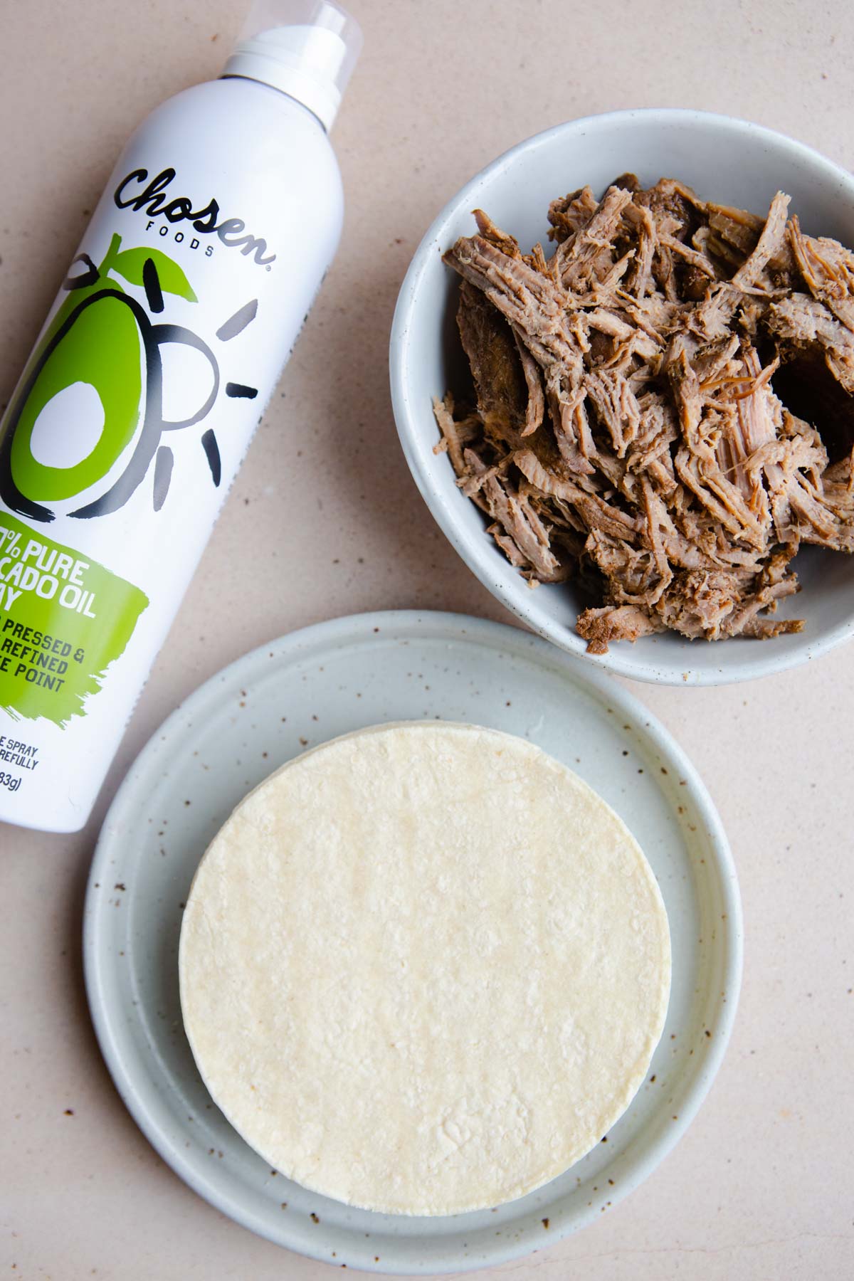 tortillas, shredded beef and avocado oil spray on a table 