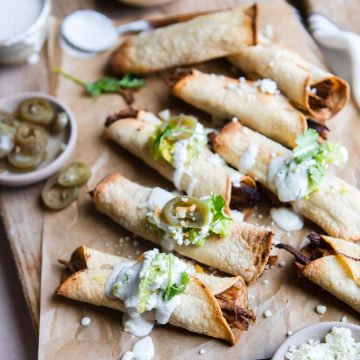 beef air fryer taquitos topped with garnishes sour cream, cheese and guacamole
