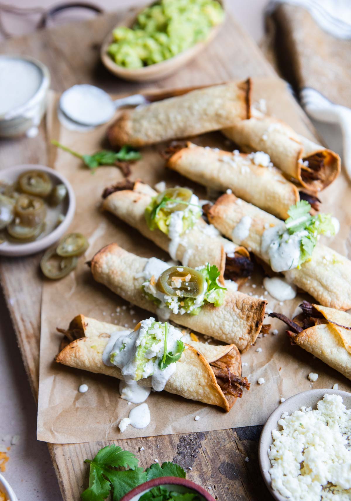 beef air fryer taquitos topped with garnishes sour cream, cheese and guacamole 