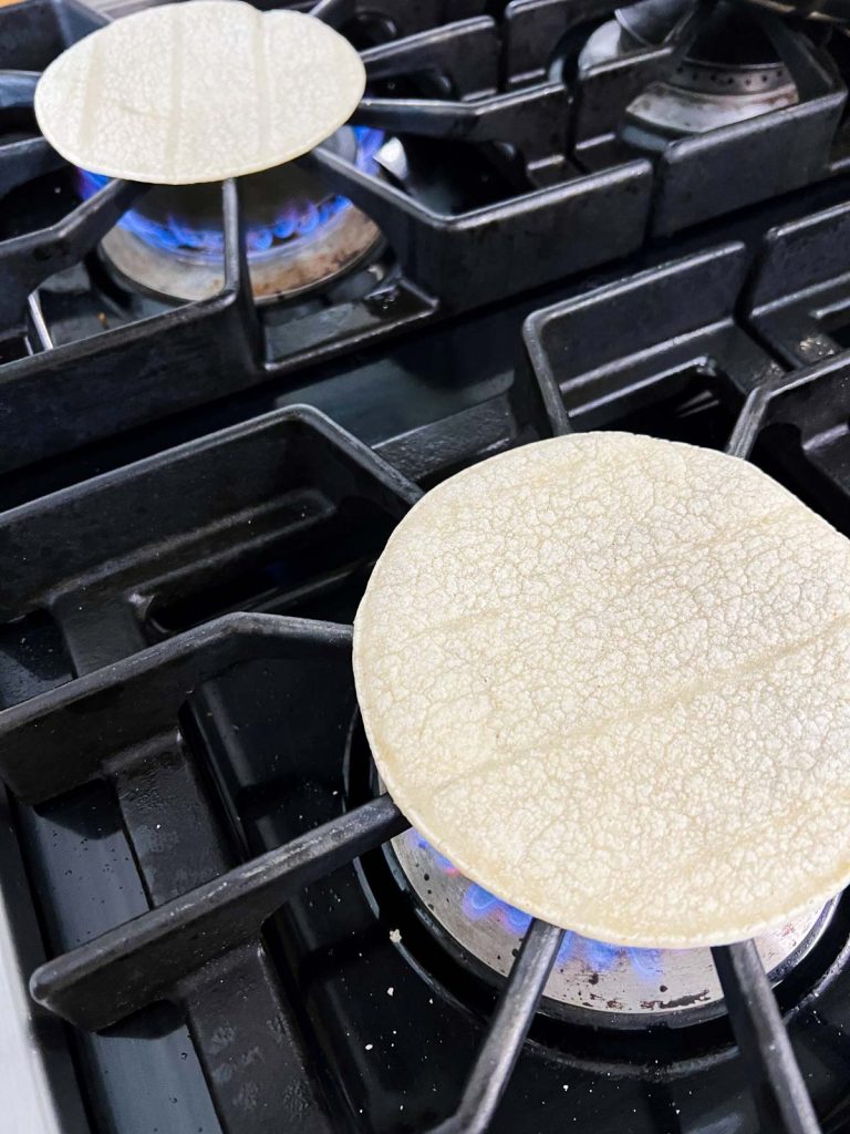 corn tortillas being heated on a stove