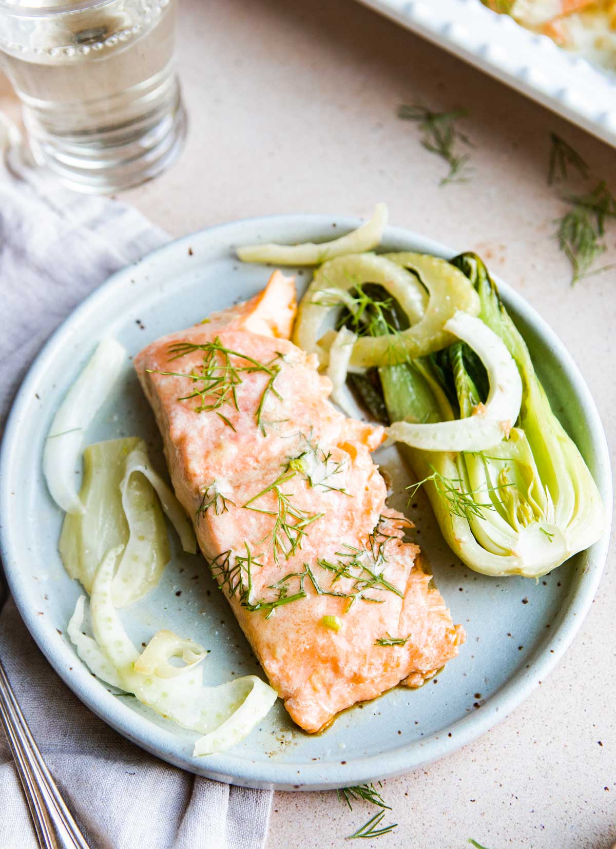small piece of salmon on a plate with baby bok choy and fennel 