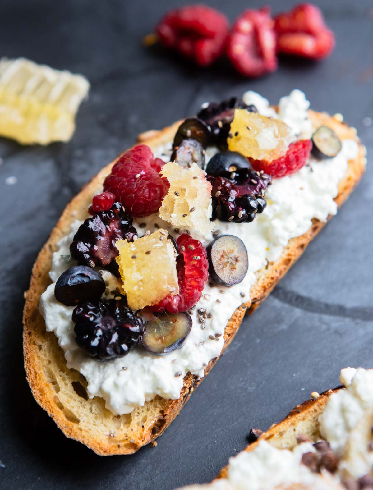 toasted whole grain bread topped with cottage cheese and fresh berries and raw honeycomb