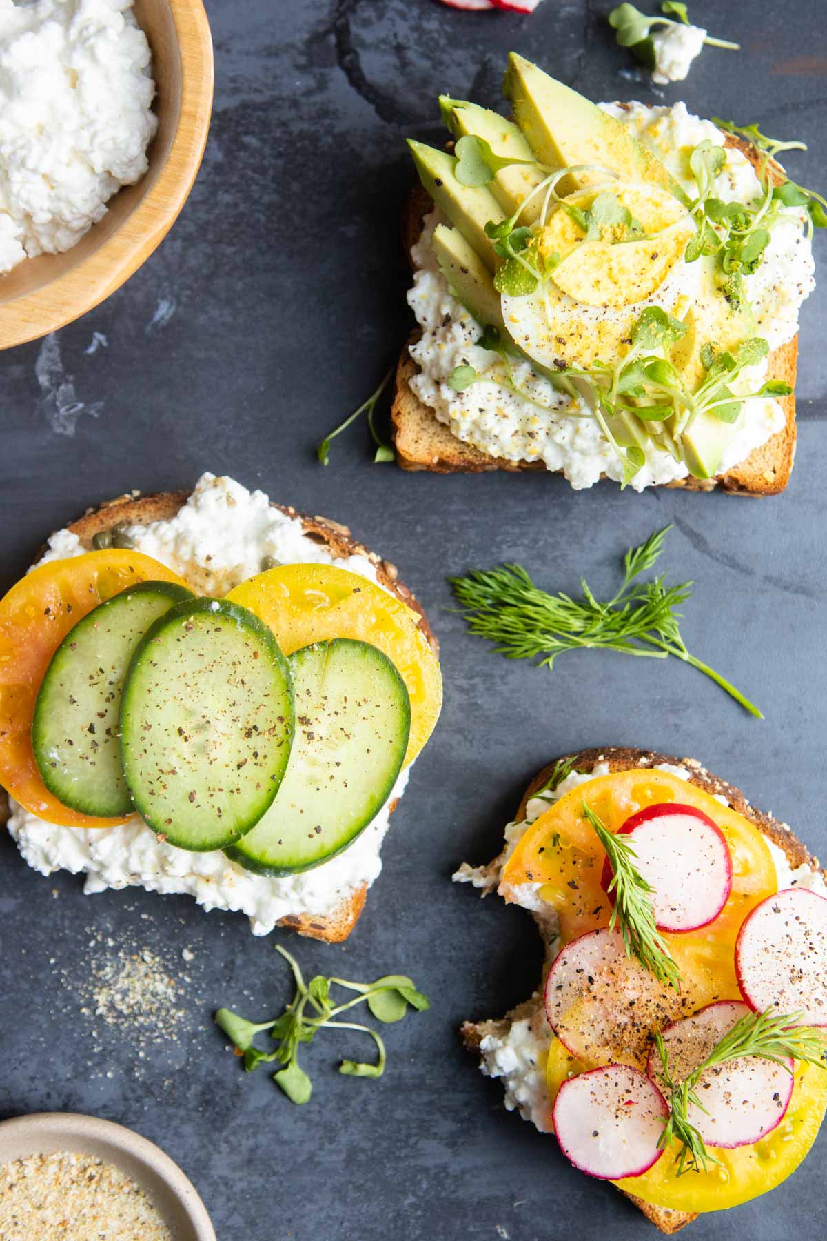 slices of toast with cottage cheese spread on top and various fresh toppings 