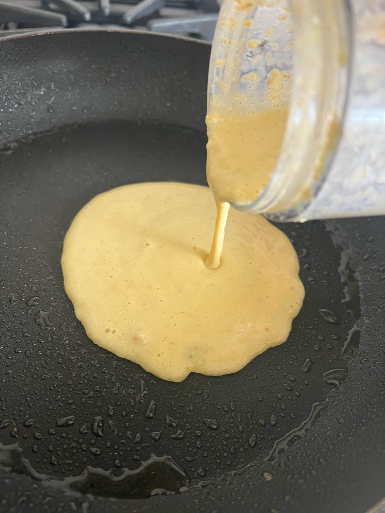 pouring high protein pancake batter into a frying pan 
