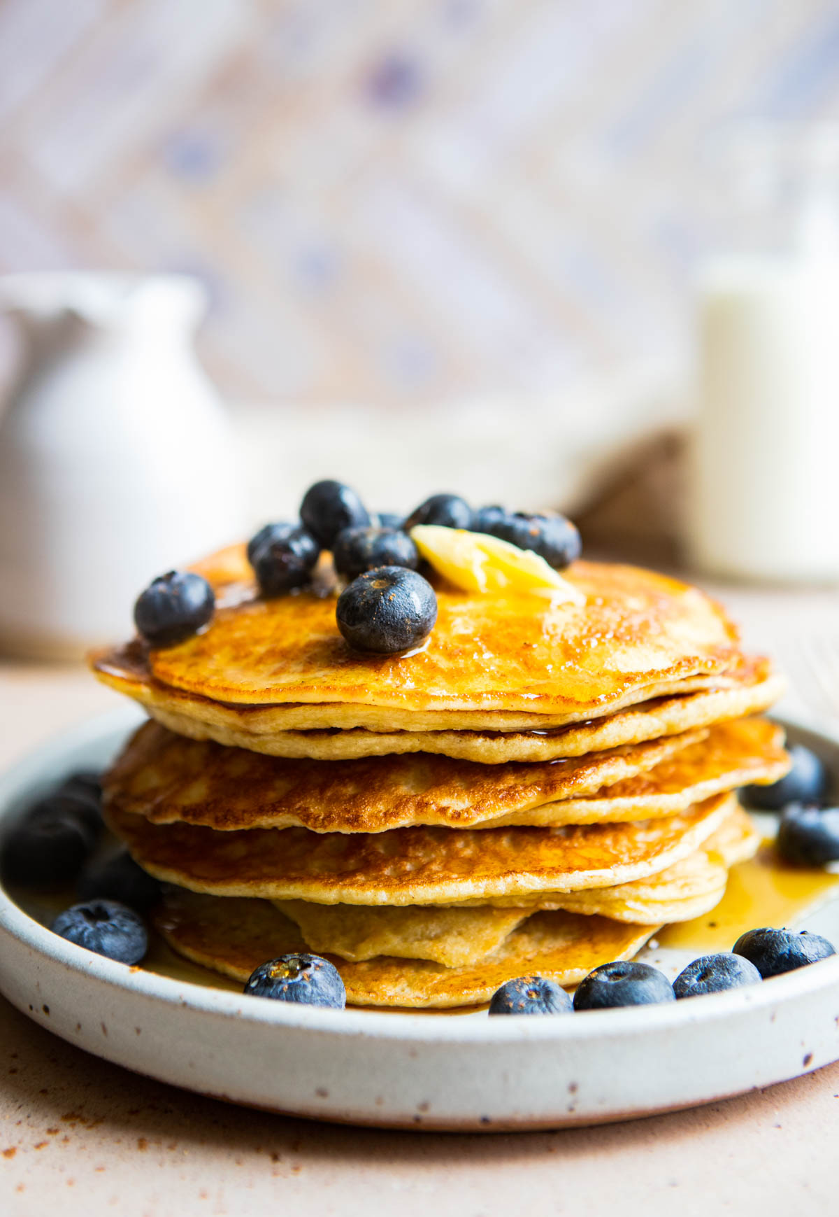 a stack of cooked protein pancakes made without protein powder and topped with butter and blueberries