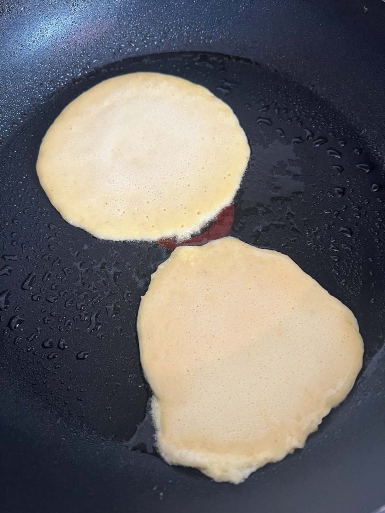 pancake batter poured into a frying pan and cooking 
