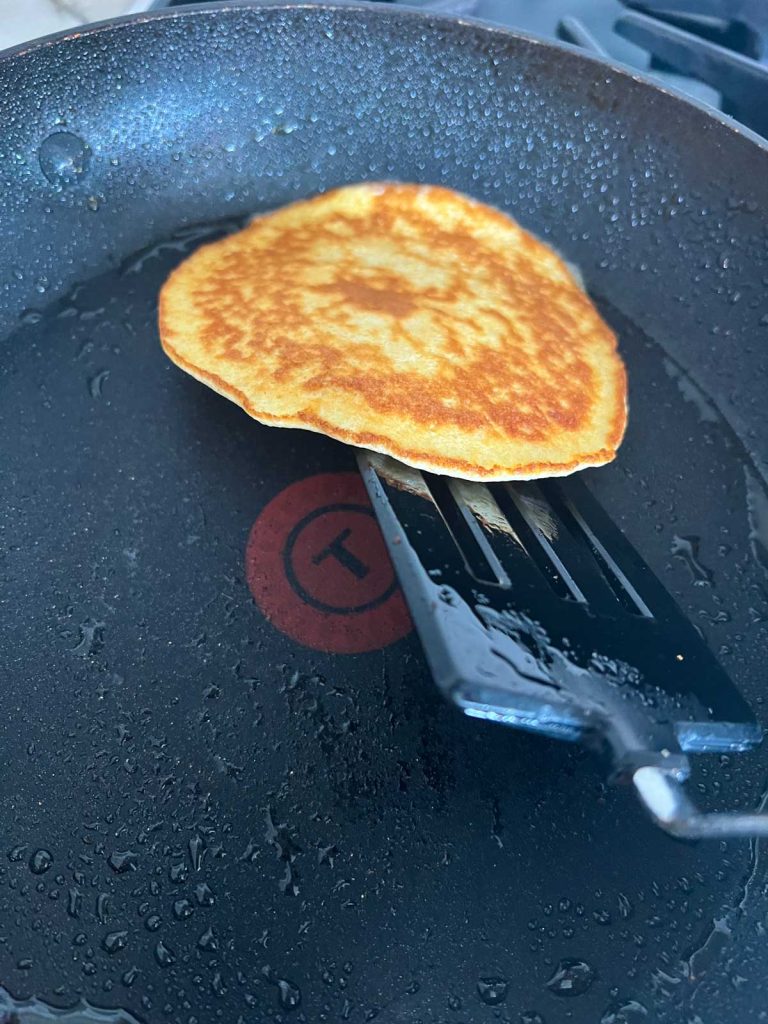 flipping a cooked pancake on a griddle 