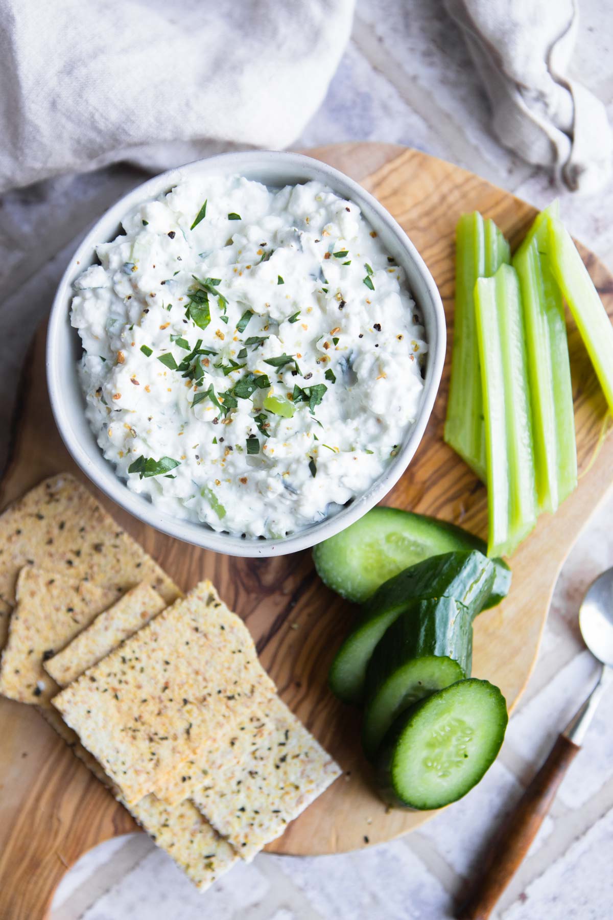 cottage cheese flavored with lemon pepper seasoning, in a white bowl and served with celery, cucumbers and crackers