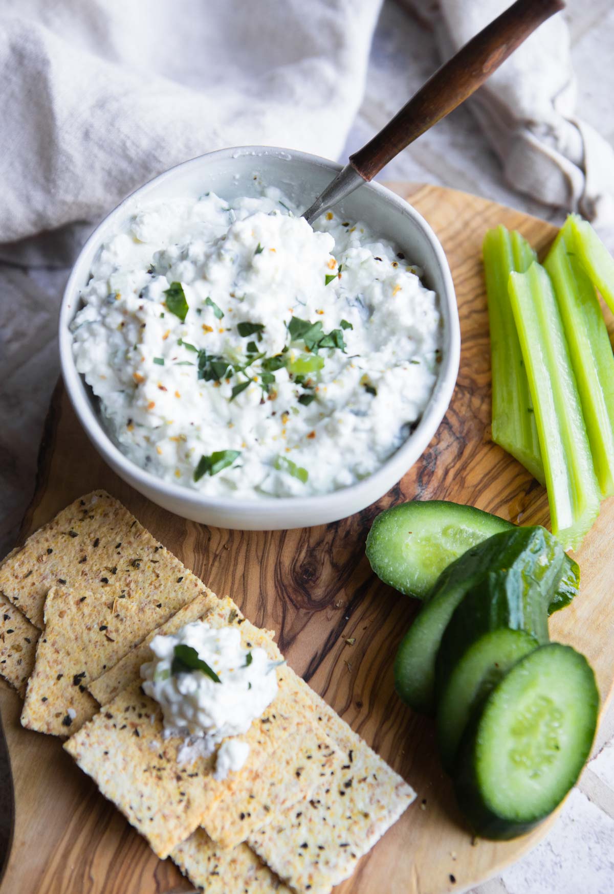 lemon pepper flavored cottage cheese dip in a white bowl served with fresh veggies and crackers