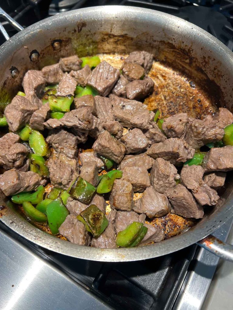 top sirloin and green peppers in a frying pan