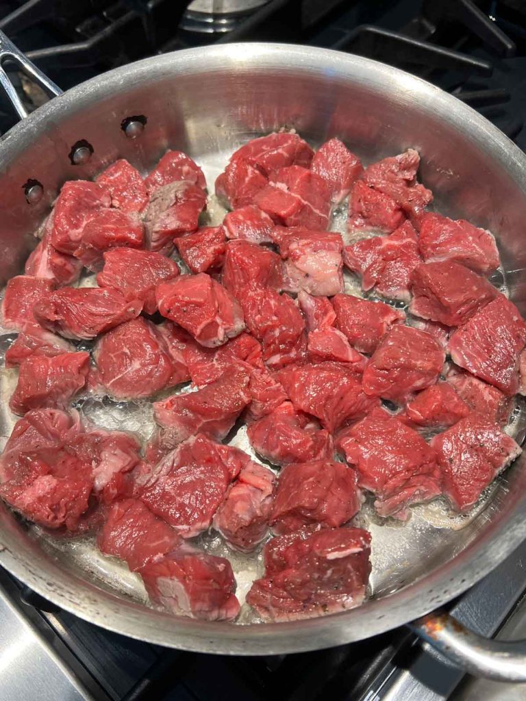 cubed top sirloin searing in a frying pan