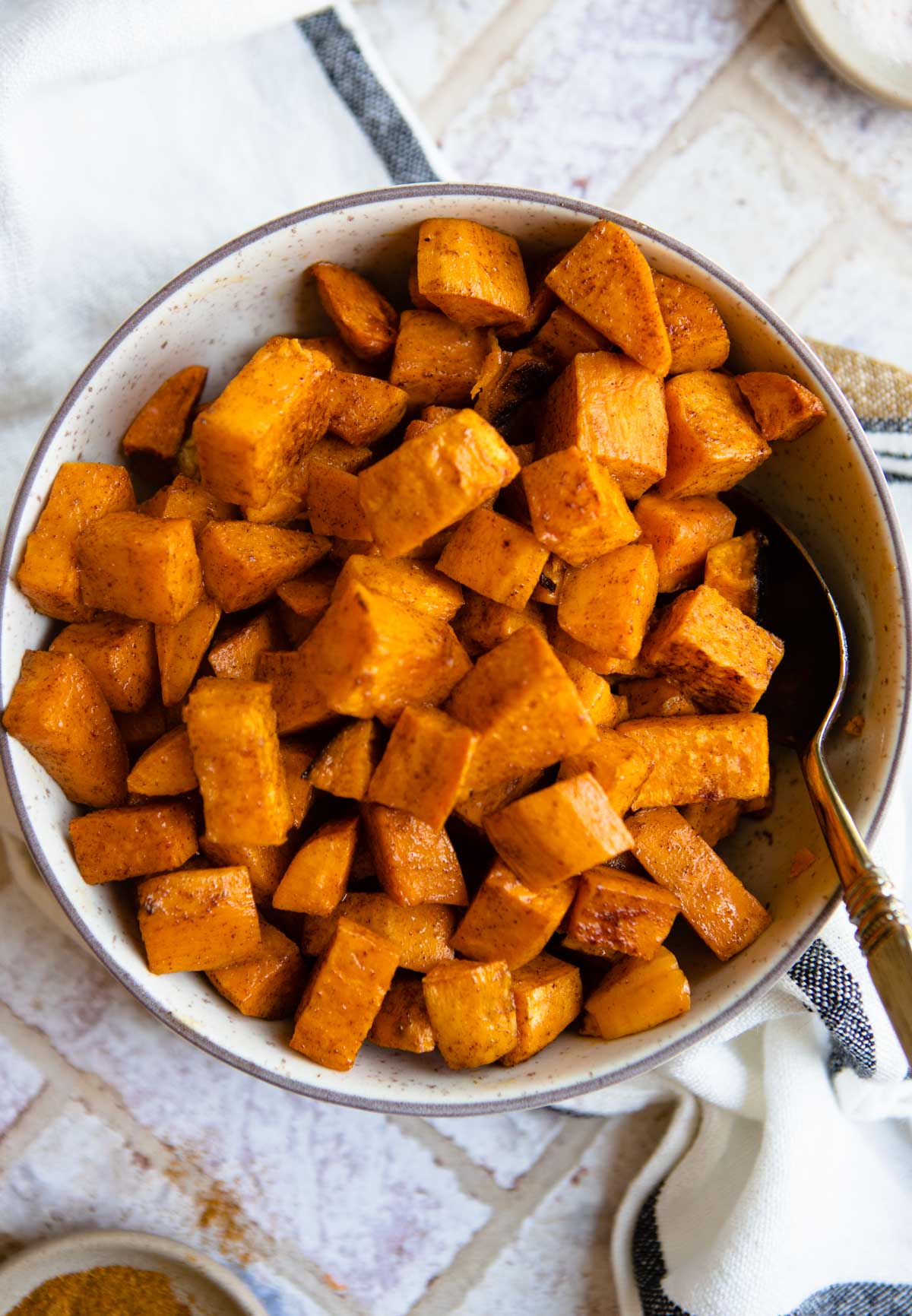 bowl of roasted sweet potatoes sprinkled with cinnamon 