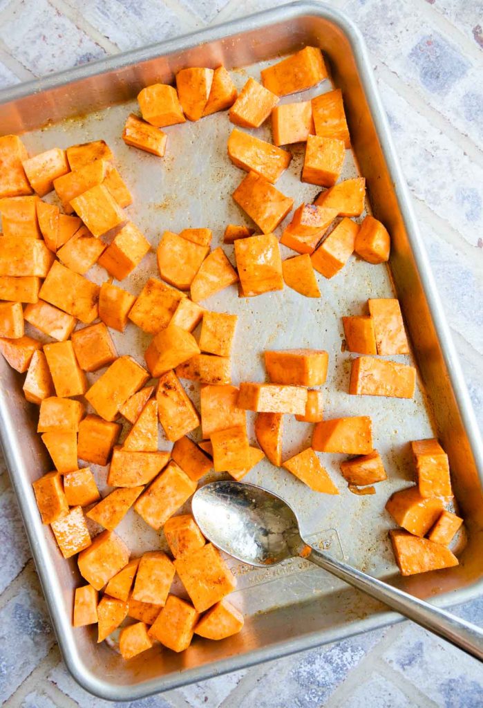 seasoned sweet potatoes on a sheet pan