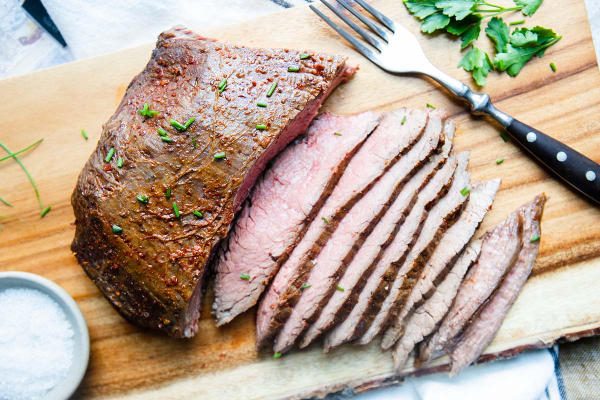 Top view of a flank steak seasoned and cooked in the air fryer and slices sliced off ready to serve.