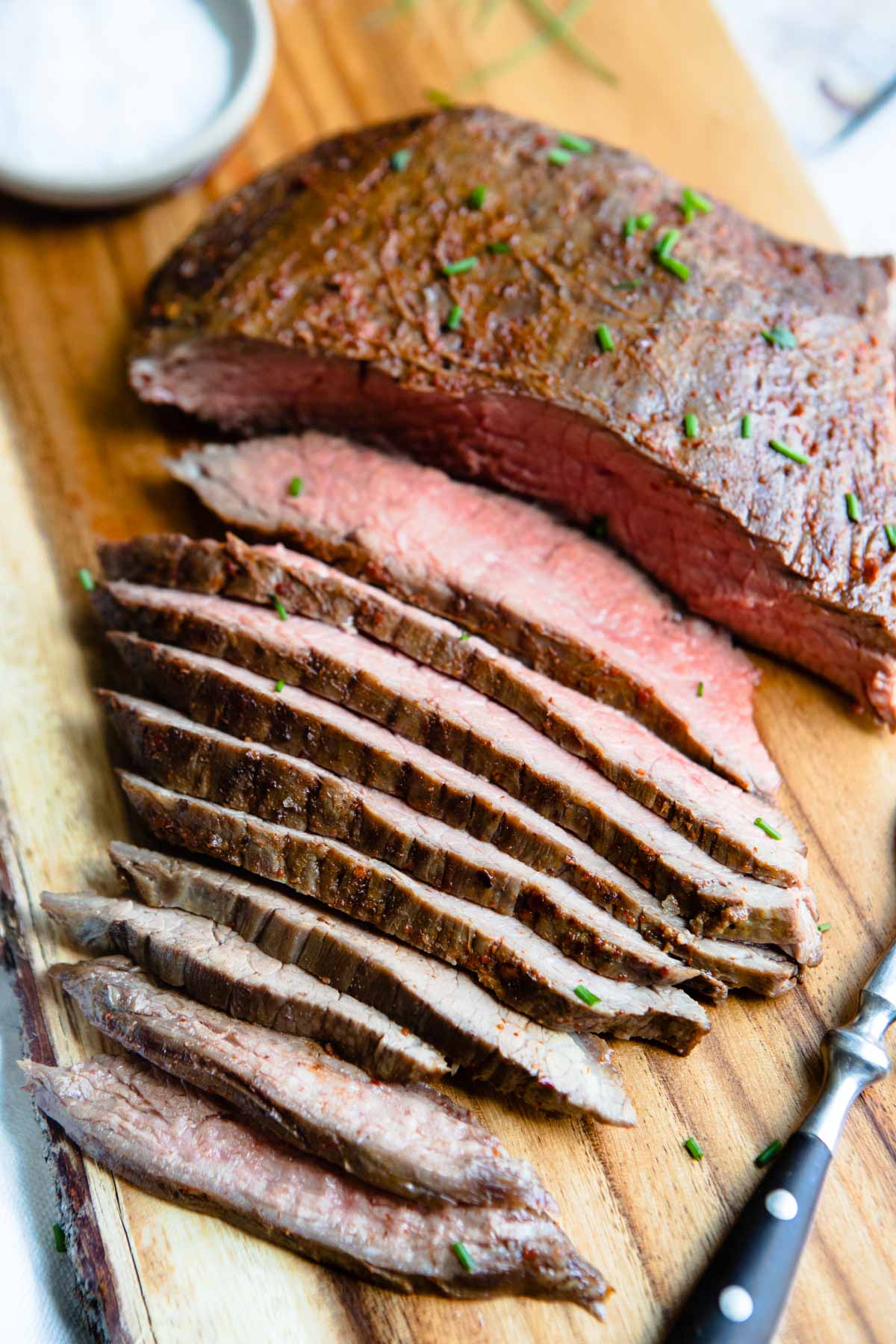 Thin slices of flank steak cut on a cutting board.