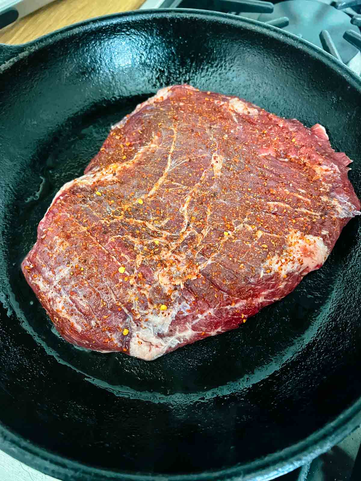 Seasoned flank steak in a skillet.