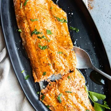 a large filet of cajun honey butter salmon on a black serving platter