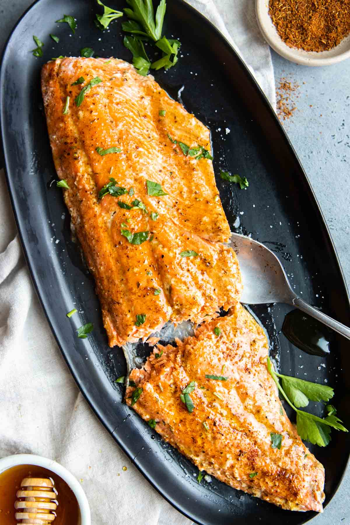 a large filet of cajun honey butter salmon on a black serving platter