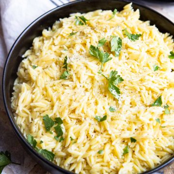 Parsley garnishes orzo pasta served in a bowl.