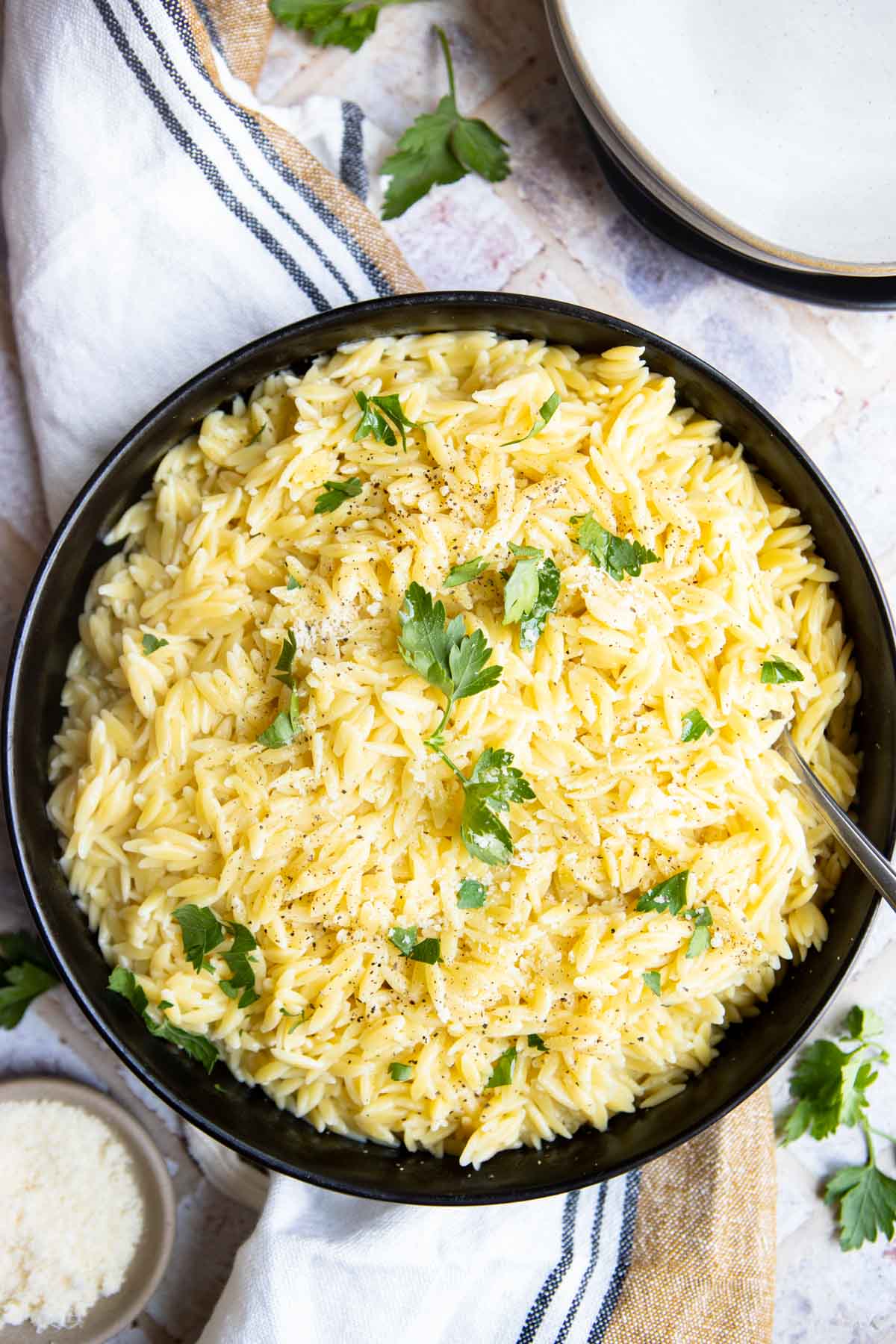 Top view of a large serving bowl of instant pot orzo with parsley garnished on top.