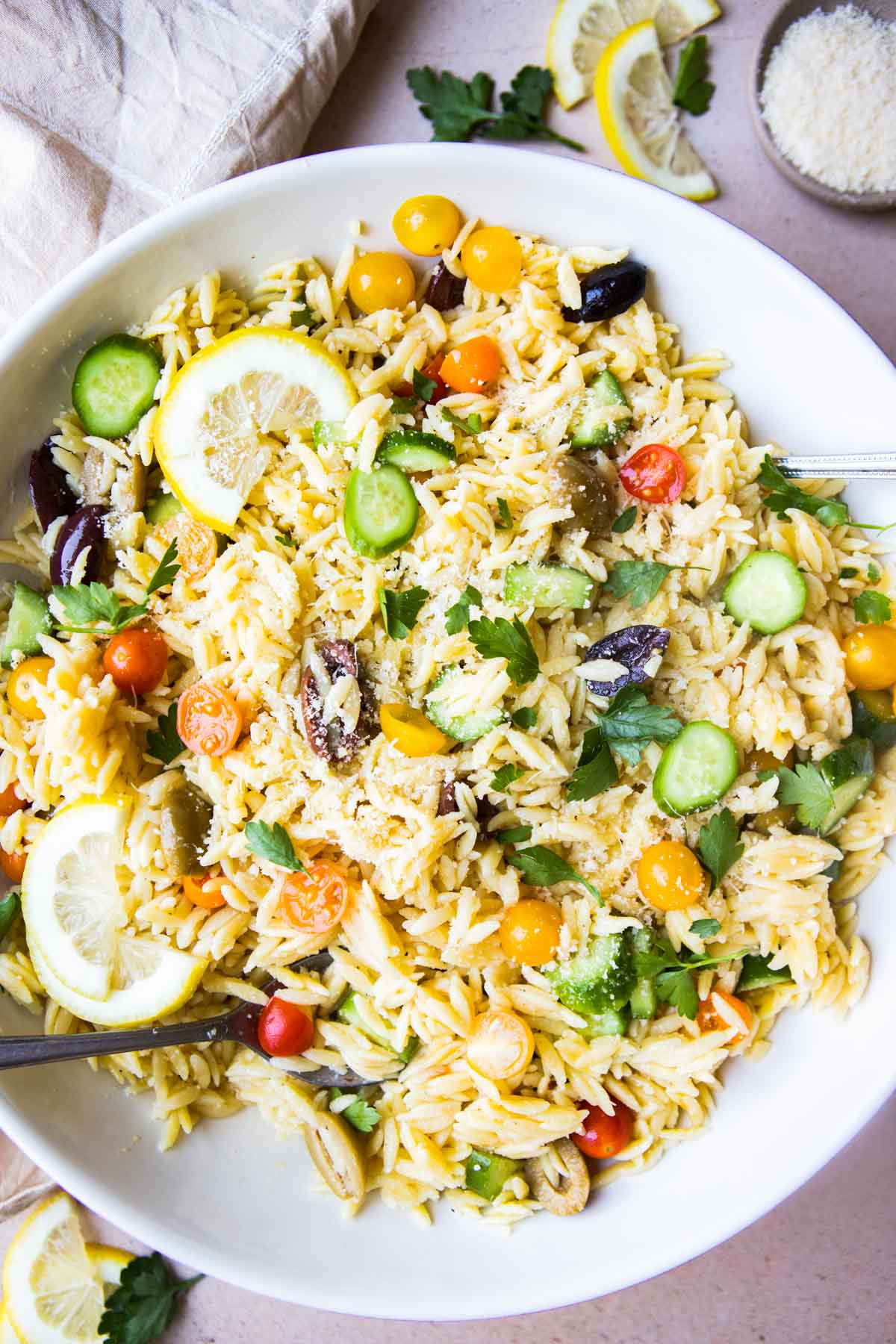 Top view of a large bowl filled with Lemon Orzo Salad and lemon slices garnished on the side.