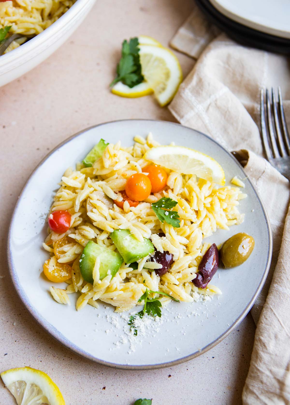 A serving of lemon orzo salad on a plate, ready to enjoy with parmesan shared over the top.
