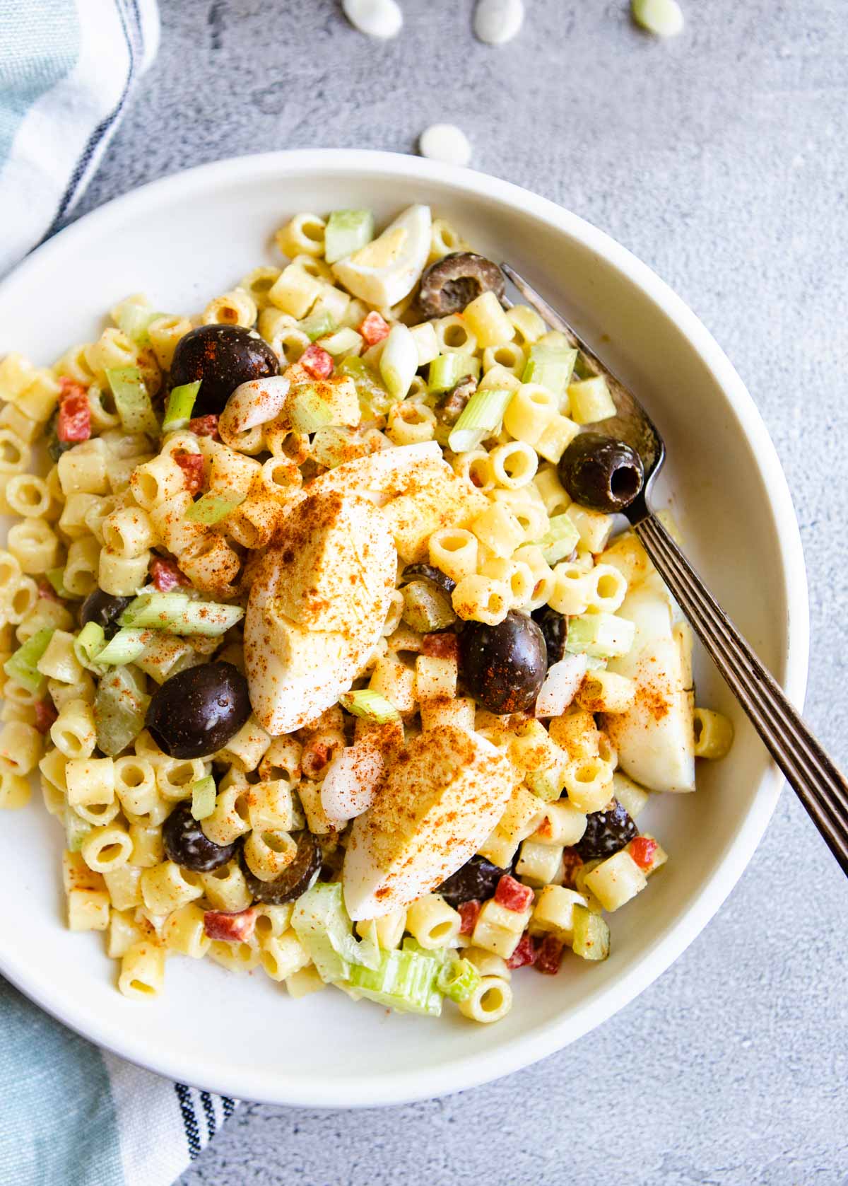 Top view of a southern macaroni salad with hardboiled eggs over the top and a fork resting in it.