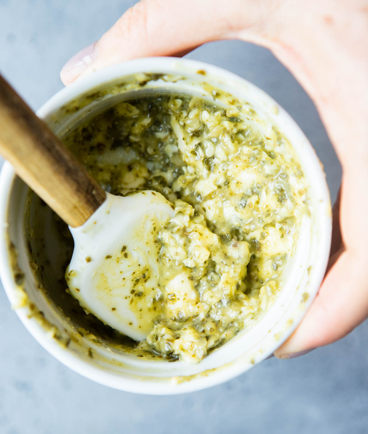 Small mixing bowl with a spatula combining butter and pesto.