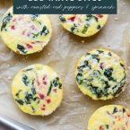 Egg bites on a parchment paper covered baking sheet with text overlay egg white bites with roasted red peppers and spinach.