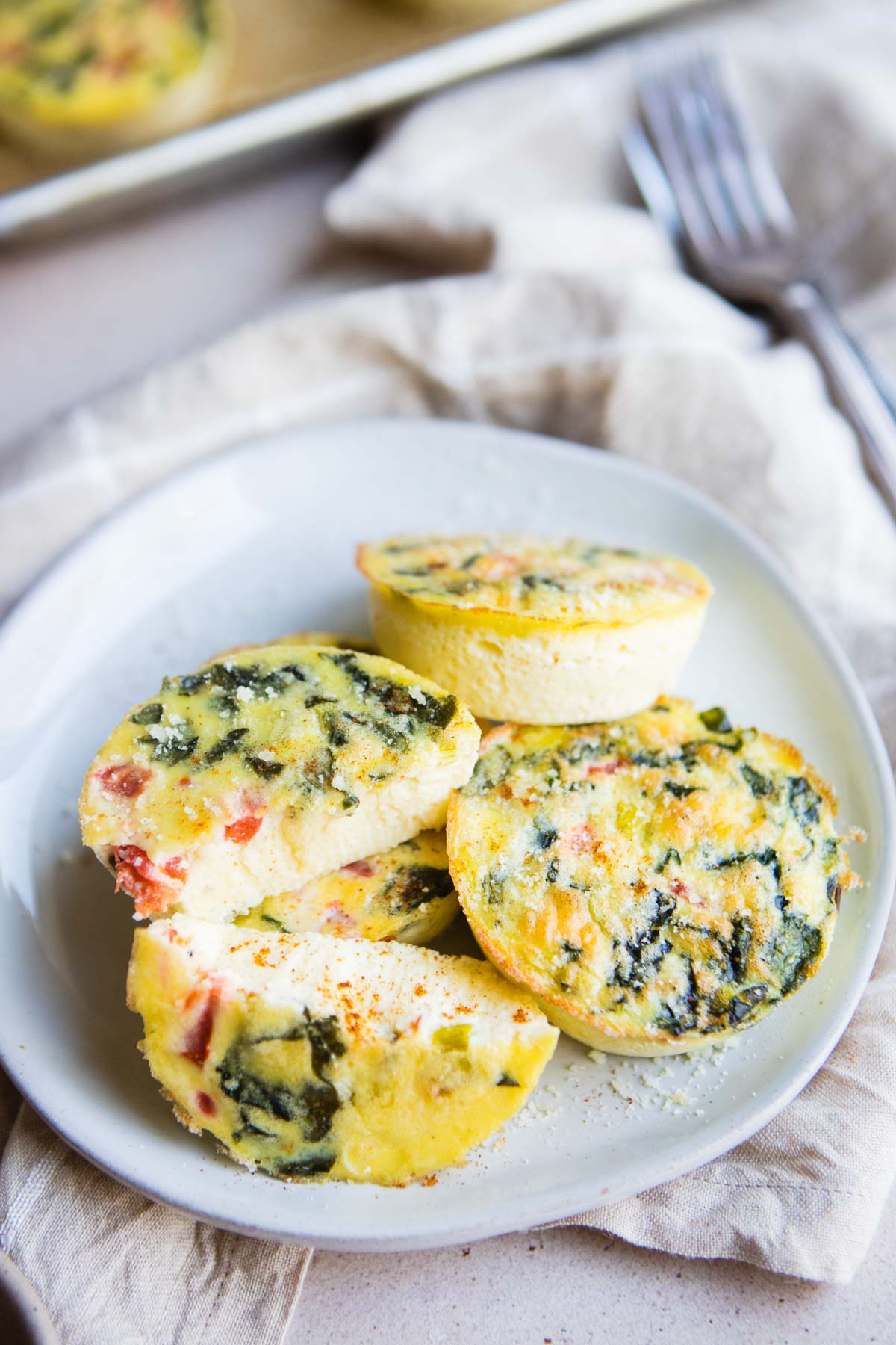 Starbucks egg white bites on a plate with one cut in half to show the veggie packed yellow center.