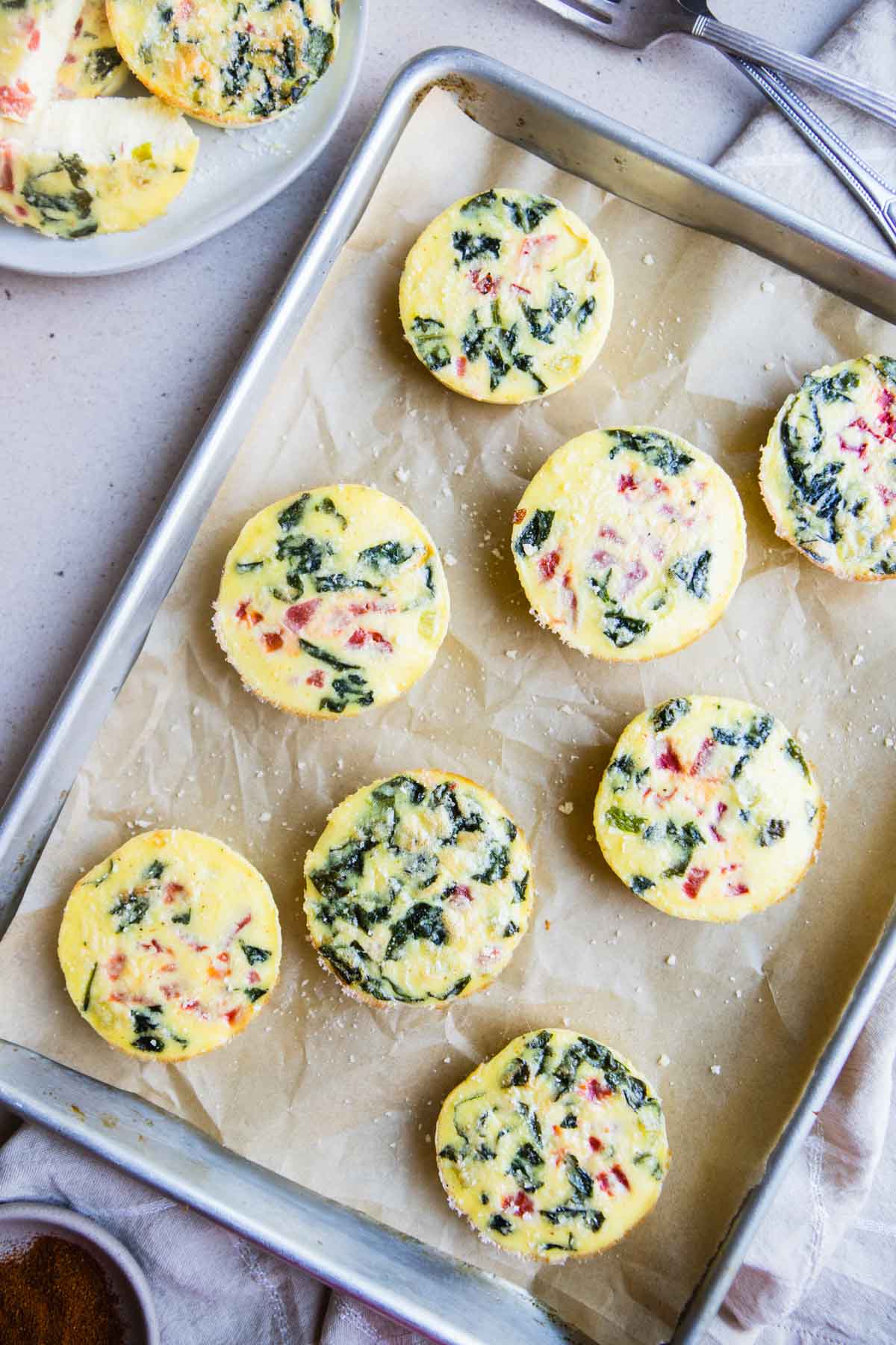 Copycat Starbucks egg white bites with red pepper and spinach laid out on a parchment loaned baking sheet