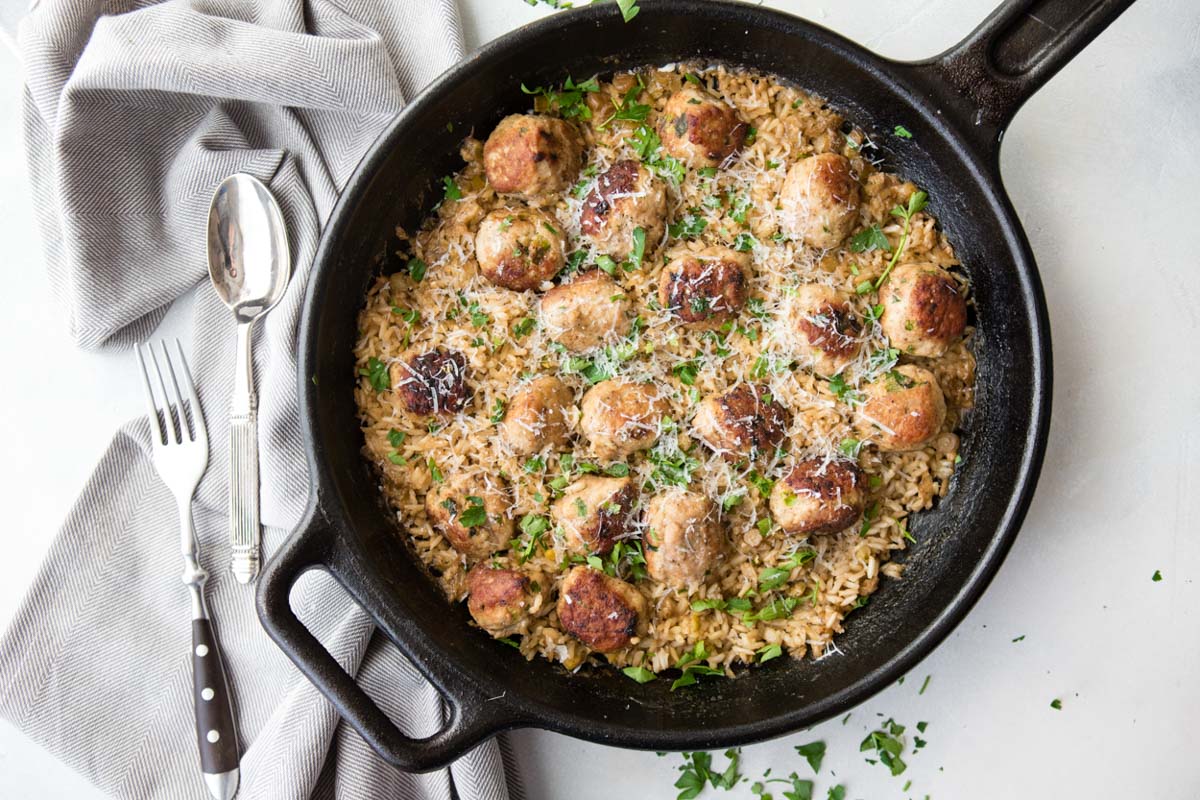 skillet turkey meatballs and rice in a black cast iron skillet garnished with parsley and parmesan cheese