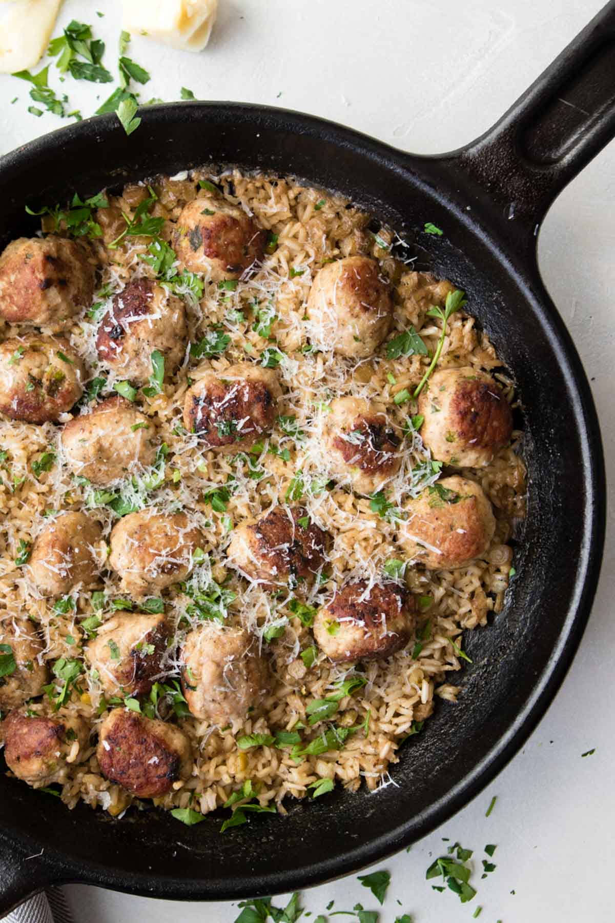 close up of a cast iron skillet filled with cooked brown rice and ground turkey meatballs 