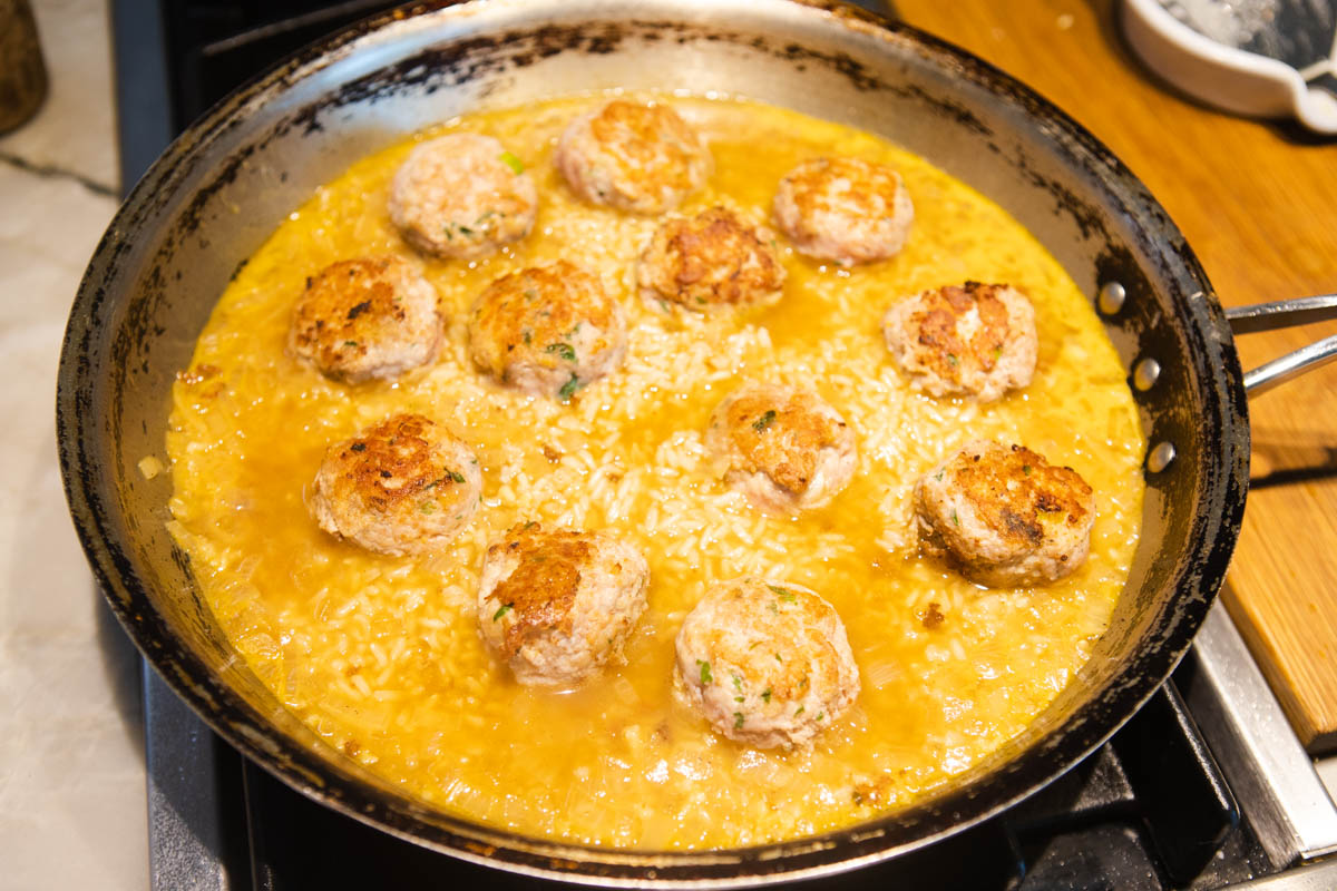 ground turkey meatballs added to partially cooked brown rice in a skillet 