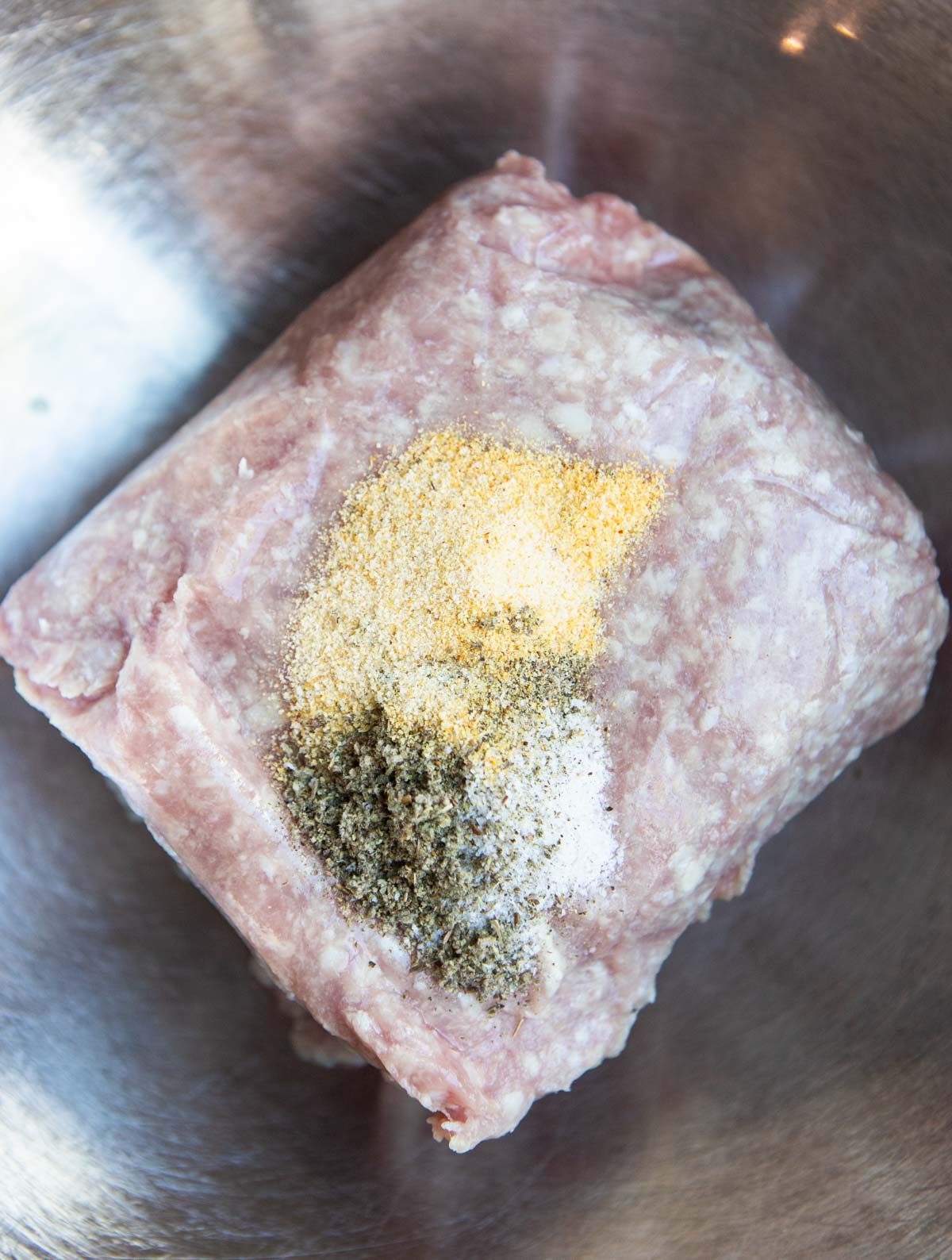 raw ground pork in a stainless steel bowl with seasonings 